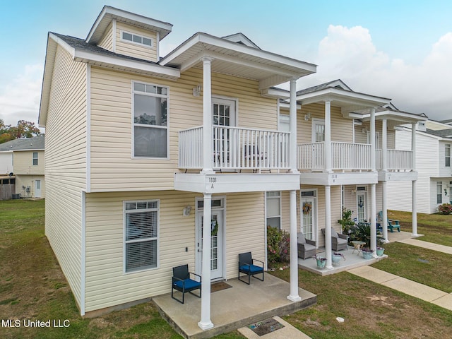 back of house featuring a balcony, a yard, and a patio