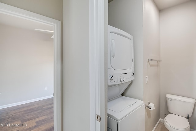 bathroom featuring hardwood / wood-style flooring, stacked washer / dryer, and toilet