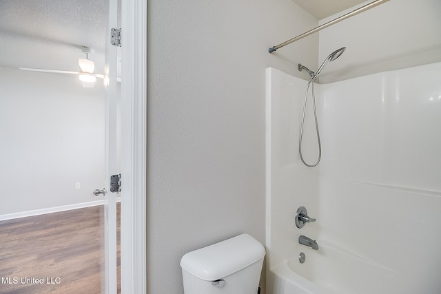 bathroom featuring hardwood / wood-style flooring, washtub / shower combination, and toilet