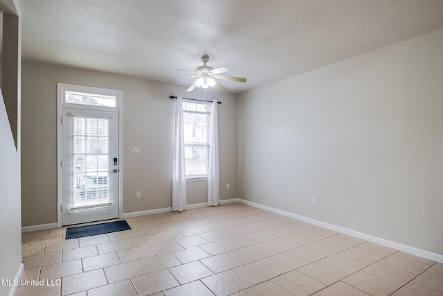 tiled foyer entrance with ceiling fan and a textured ceiling