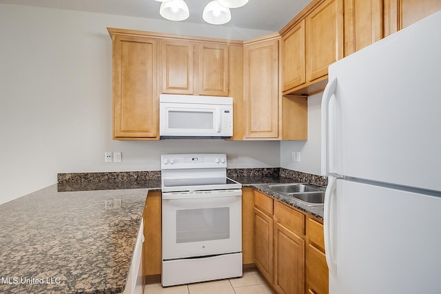 kitchen with white appliances, dark stone counters, sink, and light tile patterned floors