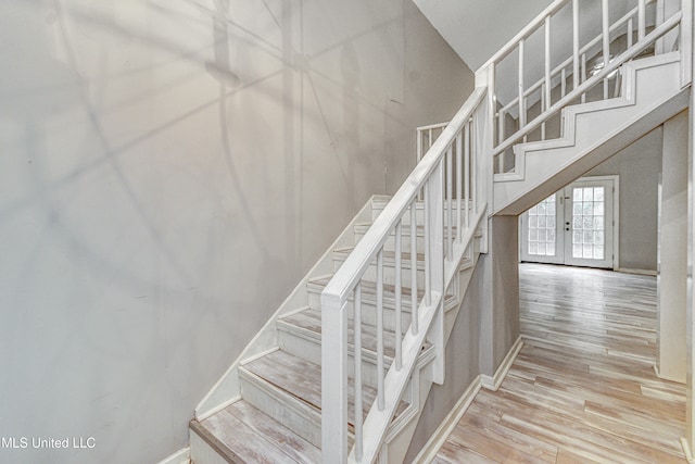 stairway featuring wood-type flooring and french doors