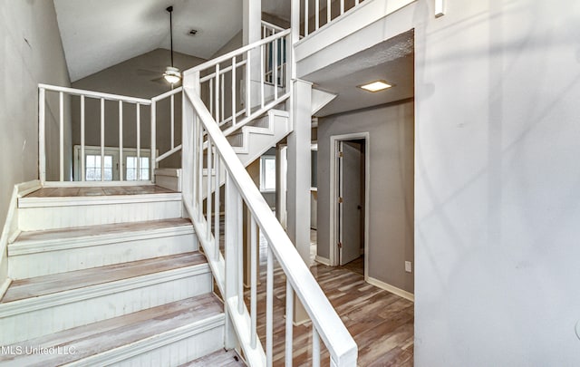 stairway with hardwood / wood-style floors, ceiling fan, and vaulted ceiling