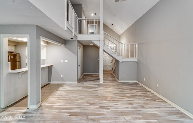 unfurnished living room with light wood-type flooring and high vaulted ceiling