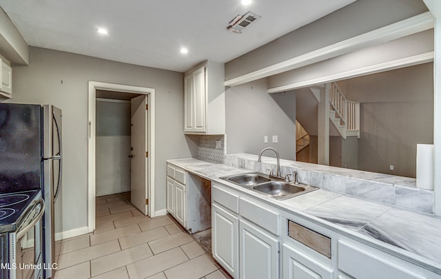 kitchen with white cabinets, stainless steel fridge, sink, and electric stove