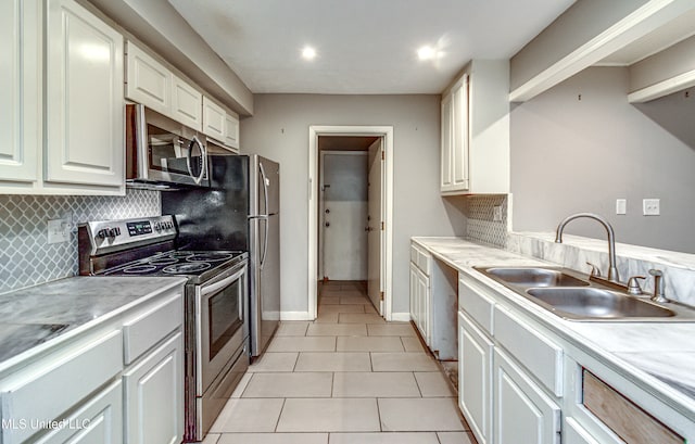 kitchen featuring stainless steel appliances, white cabinetry, sink, tasteful backsplash, and light tile patterned floors