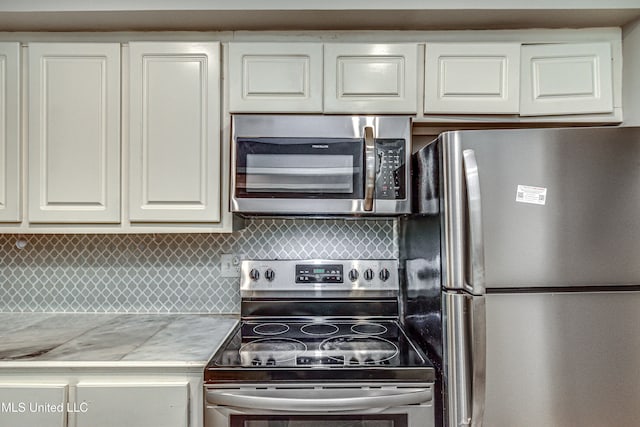 kitchen with white cabinets, decorative backsplash, and stainless steel appliances