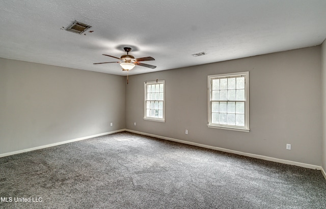 carpeted empty room featuring ceiling fan, a textured ceiling, and a healthy amount of sunlight