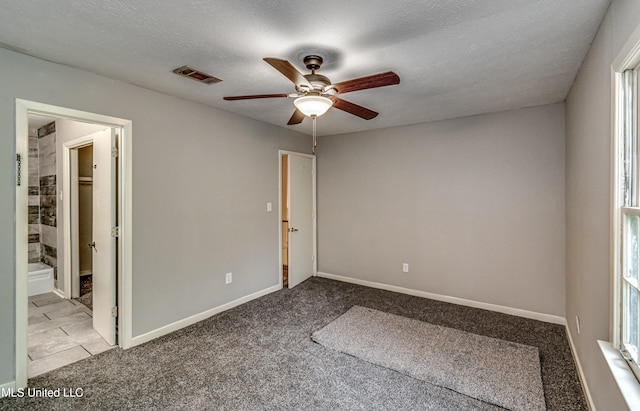 unfurnished room with a textured ceiling, light colored carpet, and ceiling fan