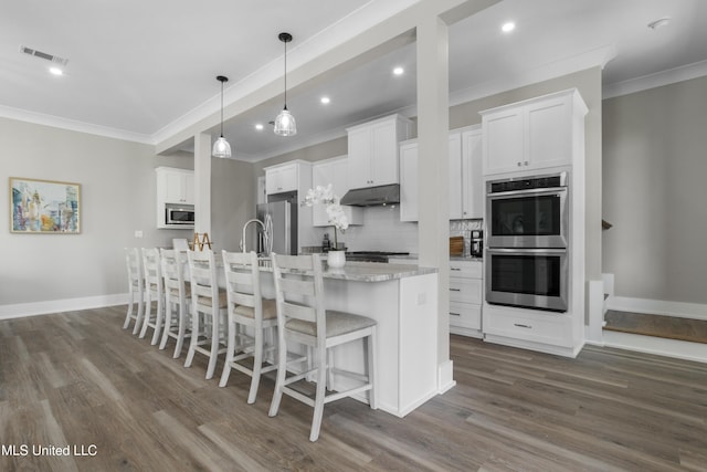 kitchen featuring dark wood-style floors, stainless steel appliances, visible vents, and under cabinet range hood