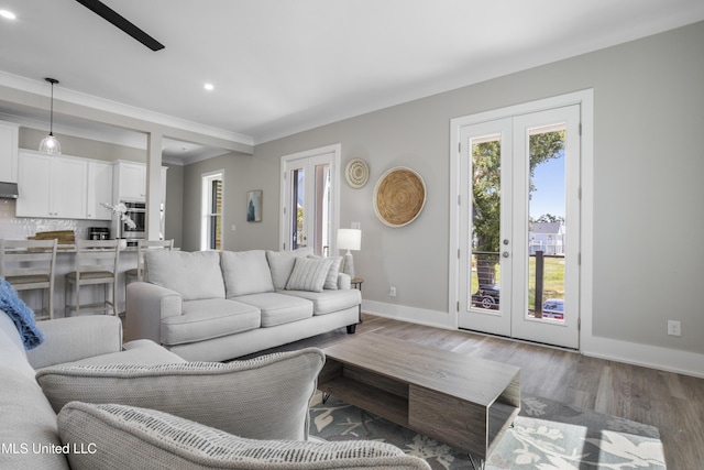 living room featuring baseboards, wood finished floors, crown molding, french doors, and recessed lighting