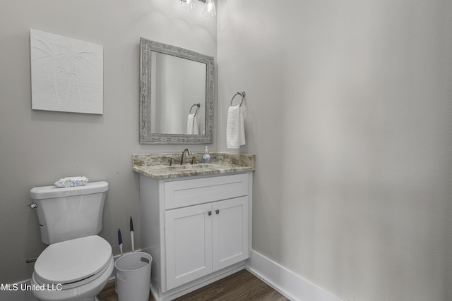 bathroom featuring baseboards, vanity, toilet, and wood finished floors