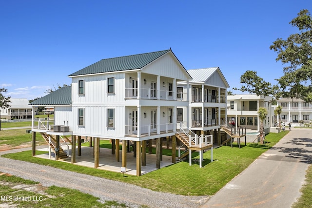 back of property with a lawn, a residential view, stairway, gravel driveway, and board and batten siding