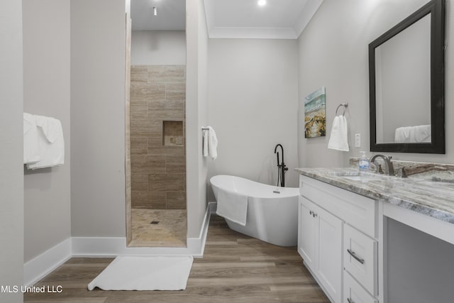 full bathroom featuring tiled shower, ornamental molding, wood finished floors, vanity, and a freestanding tub