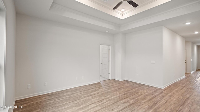 unfurnished room featuring crown molding, a tray ceiling, and light hardwood / wood-style flooring