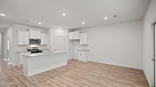 kitchen with white cabinetry, stainless steel appliances, sink, and a kitchen island with sink