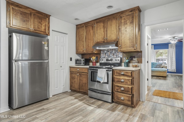 kitchen featuring backsplash, ceiling fan, light wood-type flooring, and appliances with stainless steel finishes