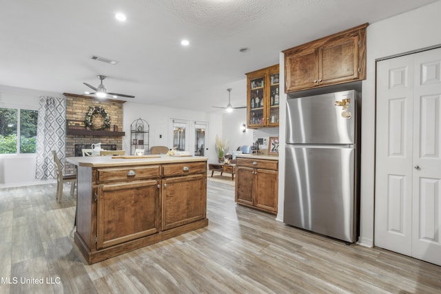 kitchen featuring french doors, light wood-type flooring, a textured ceiling, a center island, and stainless steel refrigerator