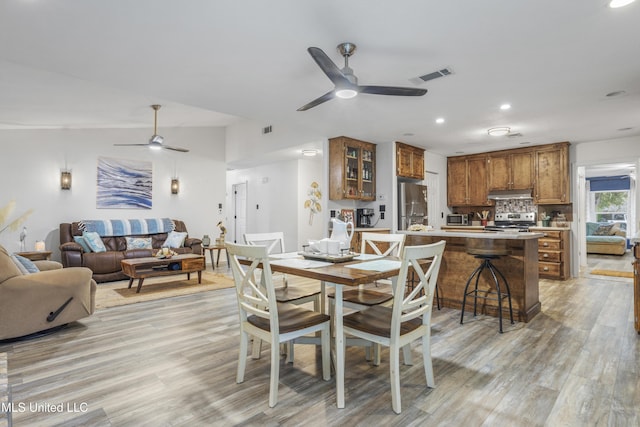 dining area with ceiling fan, light hardwood / wood-style flooring, and lofted ceiling