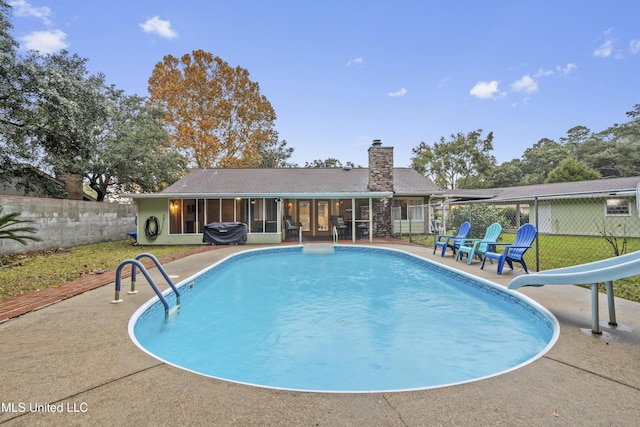 view of pool with a patio area, a sunroom, and a water slide