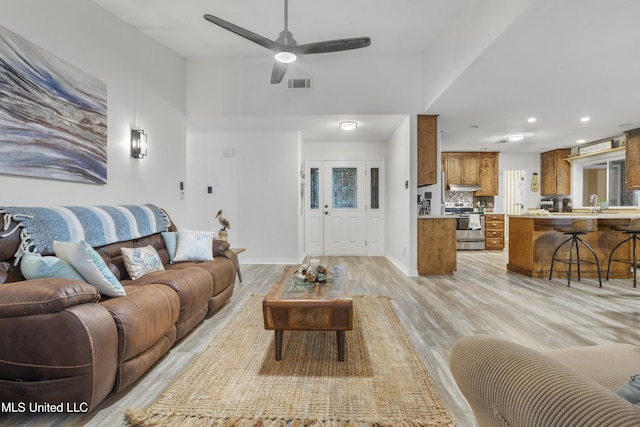 living room featuring light hardwood / wood-style floors, ceiling fan, and sink