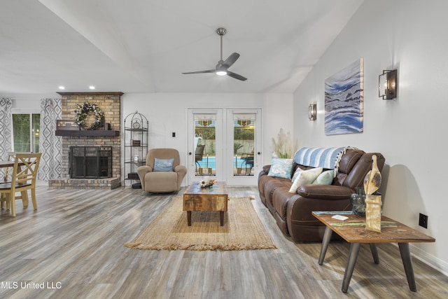 living room with hardwood / wood-style floors, a brick fireplace, ceiling fan, and lofted ceiling