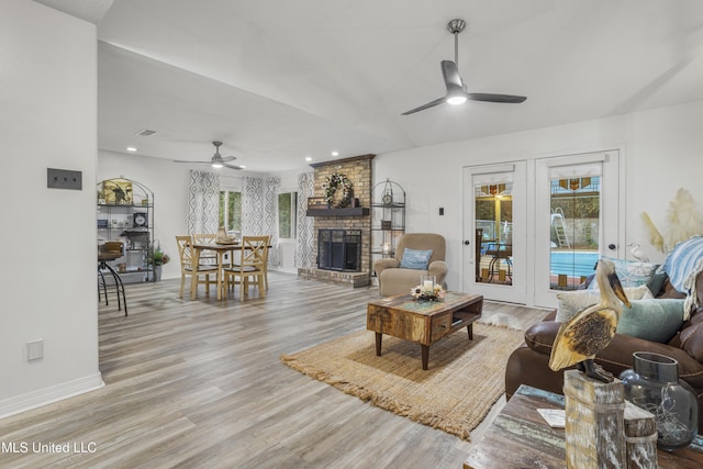 living room featuring ceiling fan, light hardwood / wood-style floors, and a brick fireplace