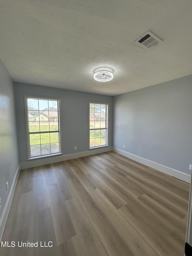 empty room featuring a textured ceiling and hardwood / wood-style floors