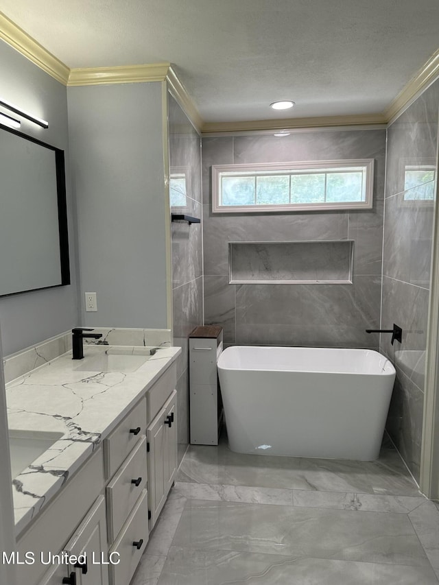 bathroom featuring ornamental molding, tile walls, a bathtub, and vanity