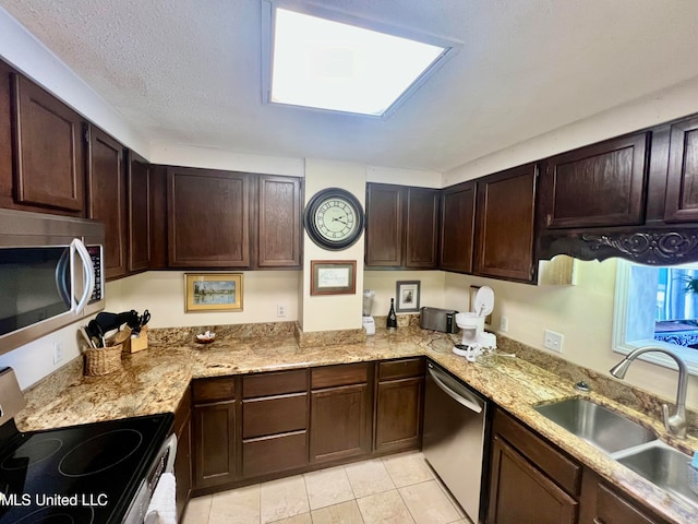 kitchen with stainless steel appliances, sink, light stone countertops, dark brown cabinetry, and a textured ceiling