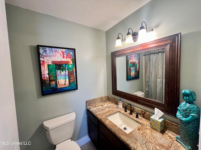 bathroom featuring vanity, a textured ceiling, and toilet