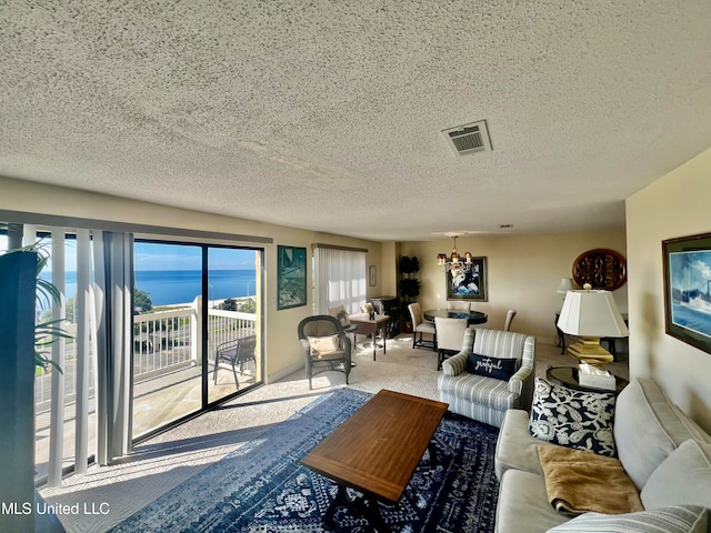 living room featuring carpet, a textured ceiling, a water view, and a healthy amount of sunlight