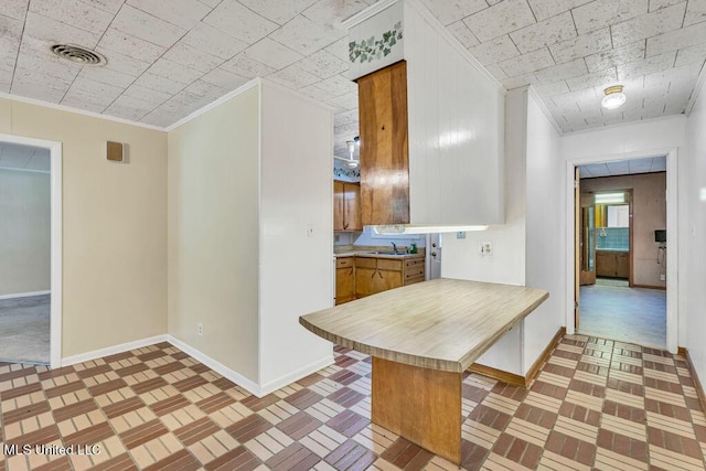 20332 Red Bird Hill Rd, Gulfport, MS 39503 - kitchen with baseboards, brown cabinetry, light countertops, crown molding, and a kitchen bar