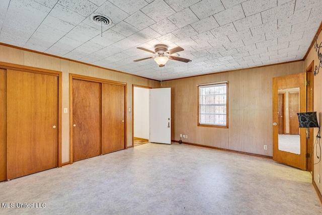 20332 Red Bird Hill Rd, Gulfport, MS 39503 - unfurnished bedroom with two closets, wooden walls, ornamental molding, ceiling fan, and baseboards
