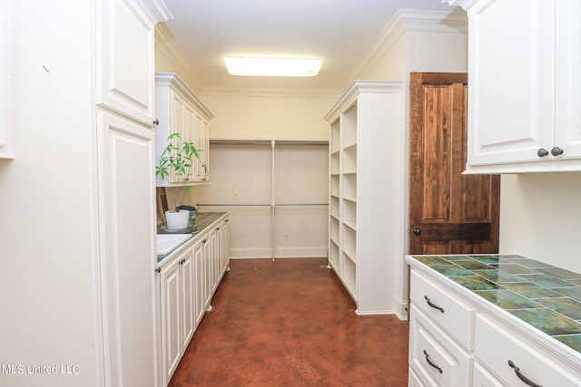 kitchen featuring white cabinetry, crown molding, tile countertops, and dark carpet