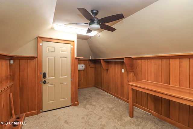 additional living space featuring light colored carpet, ceiling fan, wooden walls, and vaulted ceiling