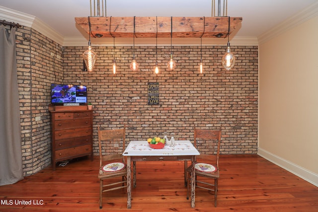 dining room with dark wood-type flooring, crown molding, and brick wall