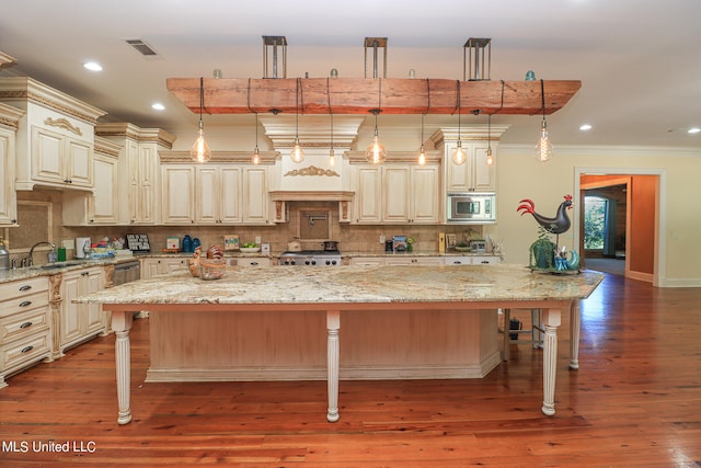 kitchen featuring a kitchen island, decorative light fixtures, stainless steel appliances, and a breakfast bar