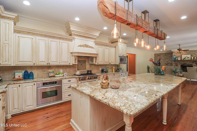 kitchen with hanging light fixtures, light stone counters, a breakfast bar, light hardwood / wood-style flooring, and stainless steel appliances