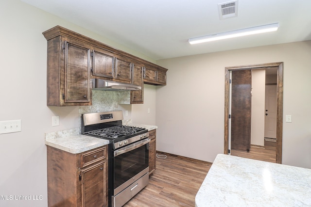 kitchen with light hardwood / wood-style flooring, dark brown cabinets, and stainless steel gas range