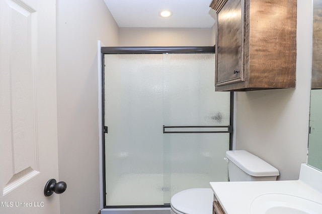 bathroom featuring vanity, a shower with shower door, and toilet