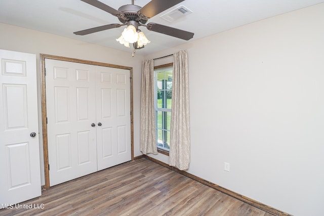 unfurnished bedroom featuring a closet, wood-type flooring, and ceiling fan