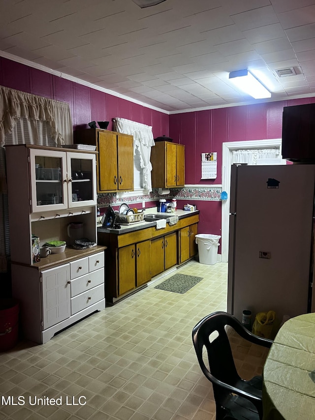 742 Brandon Ave, Jackson, MS 39209 - kitchen featuring freestanding refrigerator, ornamental molding, light flooring, and brown cabinets