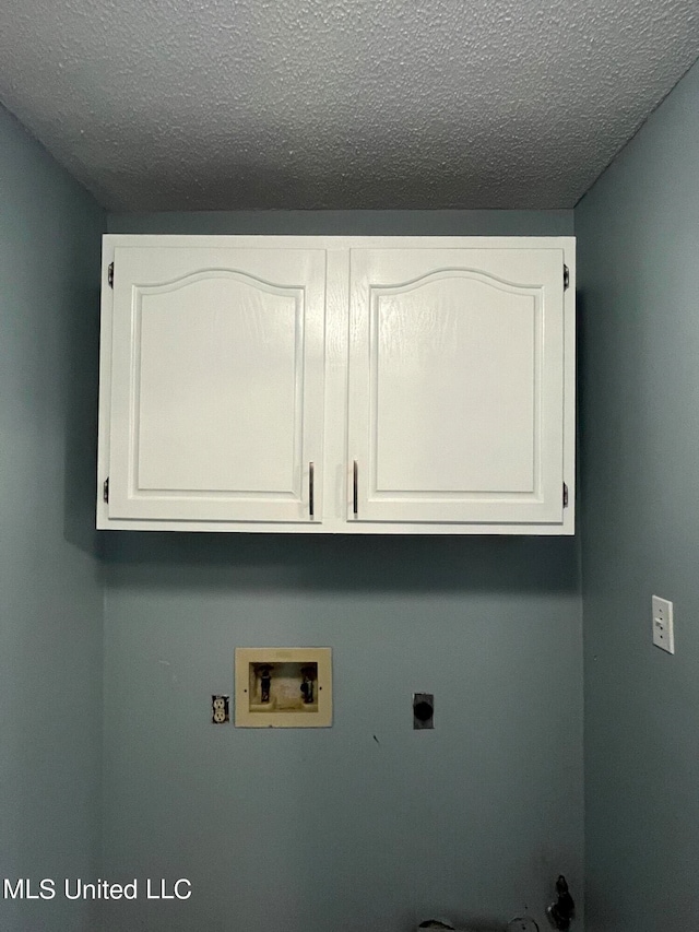 clothes washing area with cabinets, a textured ceiling, washer hookup, and electric dryer hookup