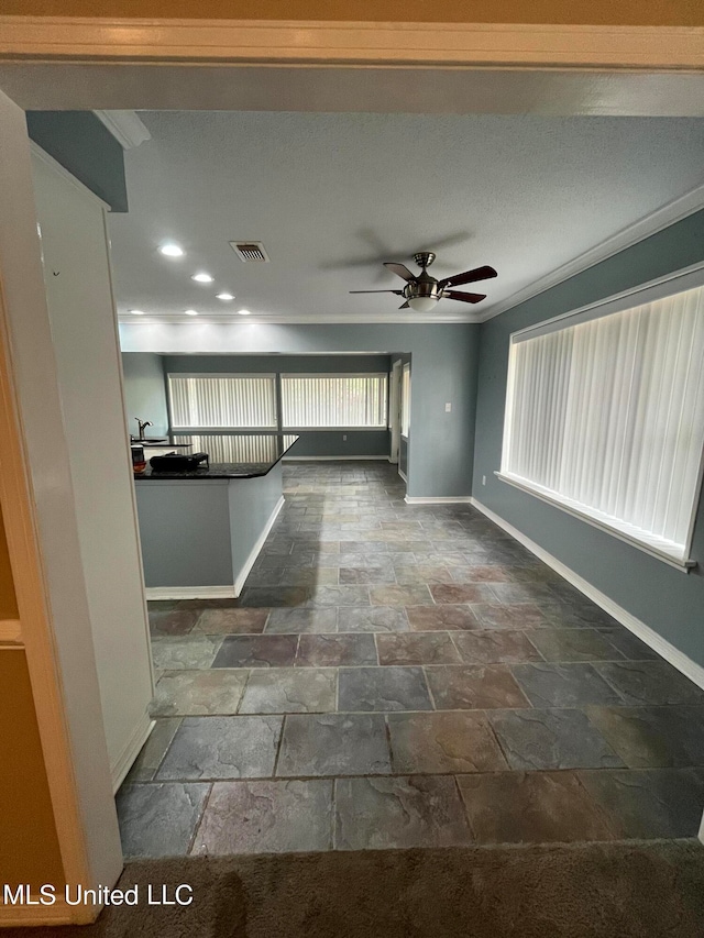 unfurnished living room with ornamental molding and ceiling fan