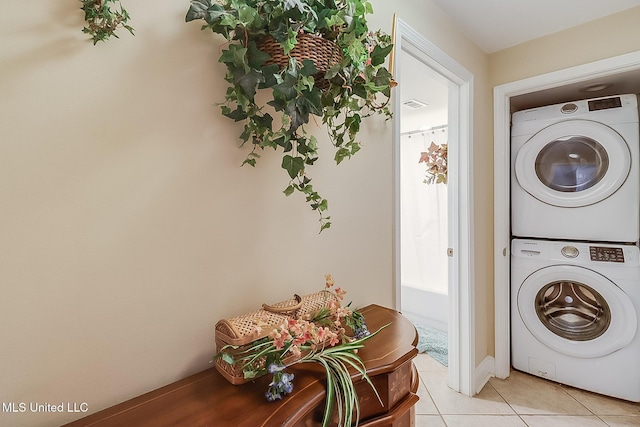laundry room featuring stacked washing machine and dryer and light tile patterned floors
