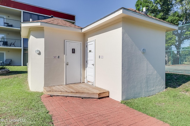 property entrance featuring stucco siding and a yard