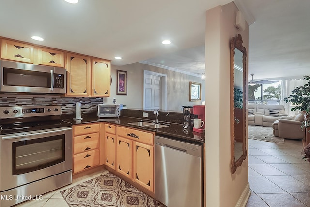 kitchen with appliances with stainless steel finishes, a sink, light tile patterned floors, decorative backsplash, and ornamental molding