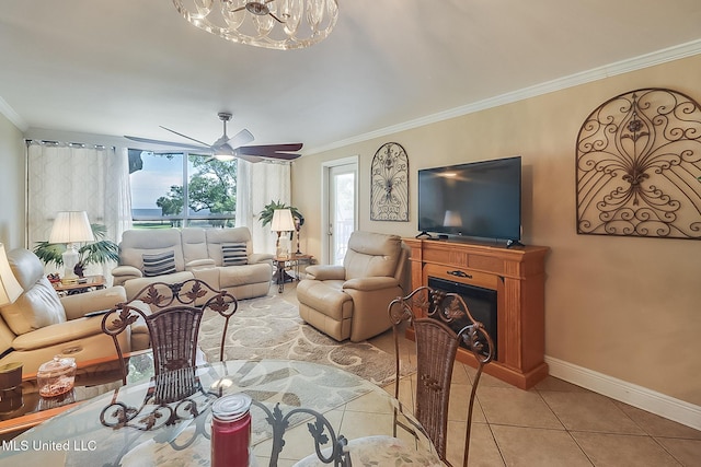 living room featuring ornamental molding, a chandelier, baseboards, light tile patterned flooring, and a ceiling fan