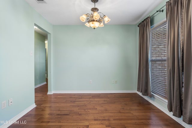 unfurnished room with an inviting chandelier and dark hardwood / wood-style floors